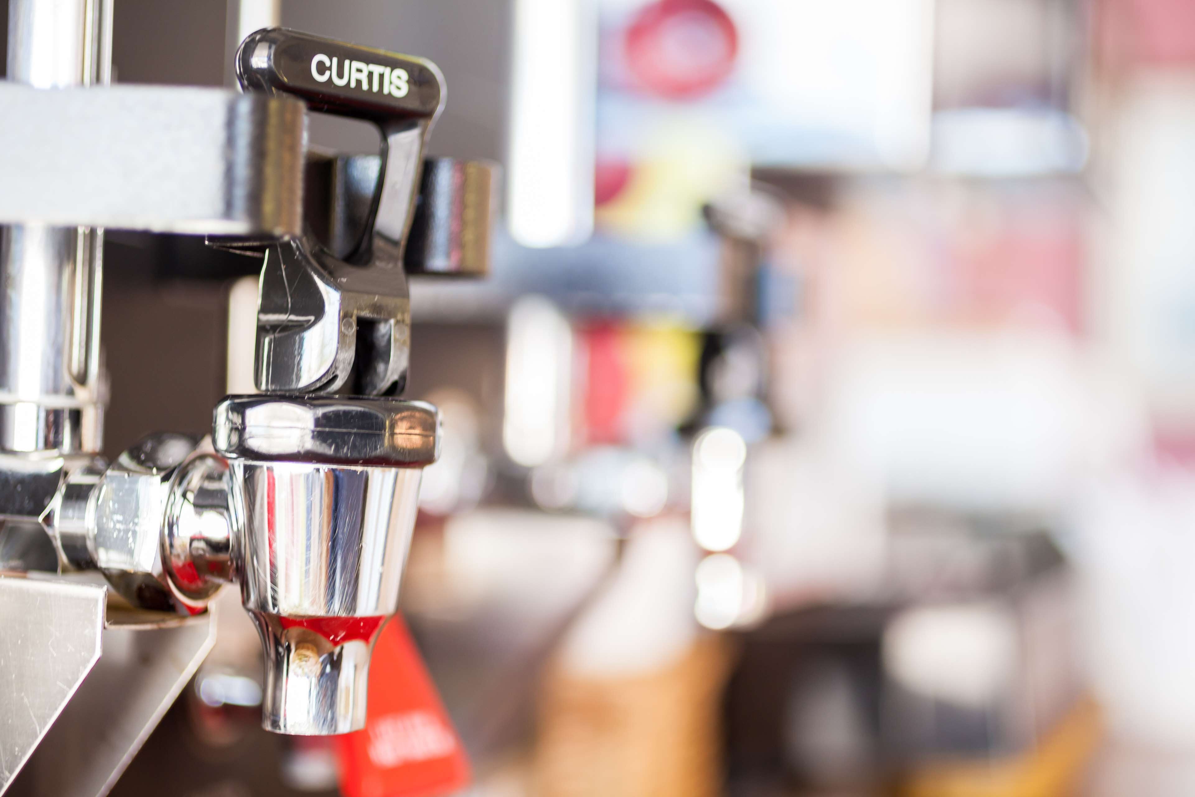 Un primo piano di una macchina da caffè con l'etichetta "CURTIS", che indica una macchina per espresso di marca.