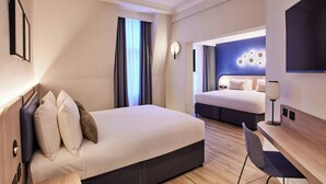 A modern hotel room with a large bed, a desk, and a TV. - Thistle London Bloomsbury Park (London)