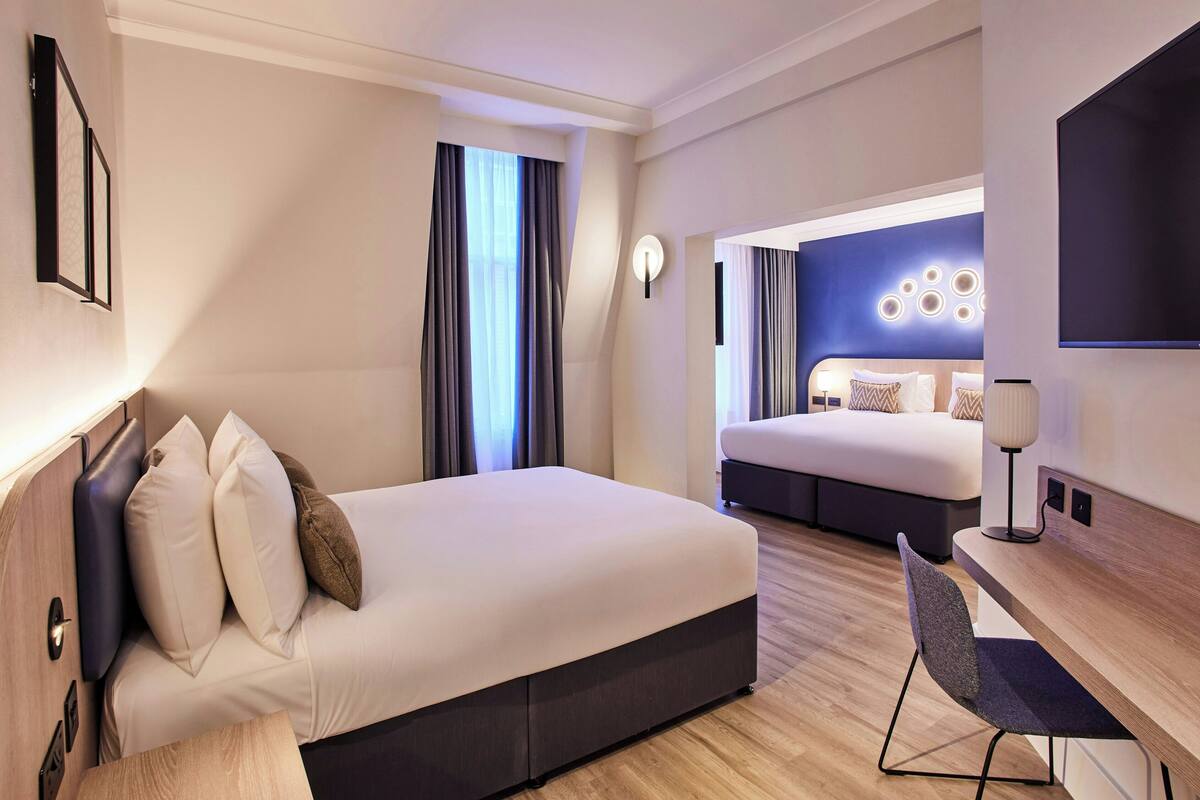 A modern hotel room with a large bed, a desk, and a TV.