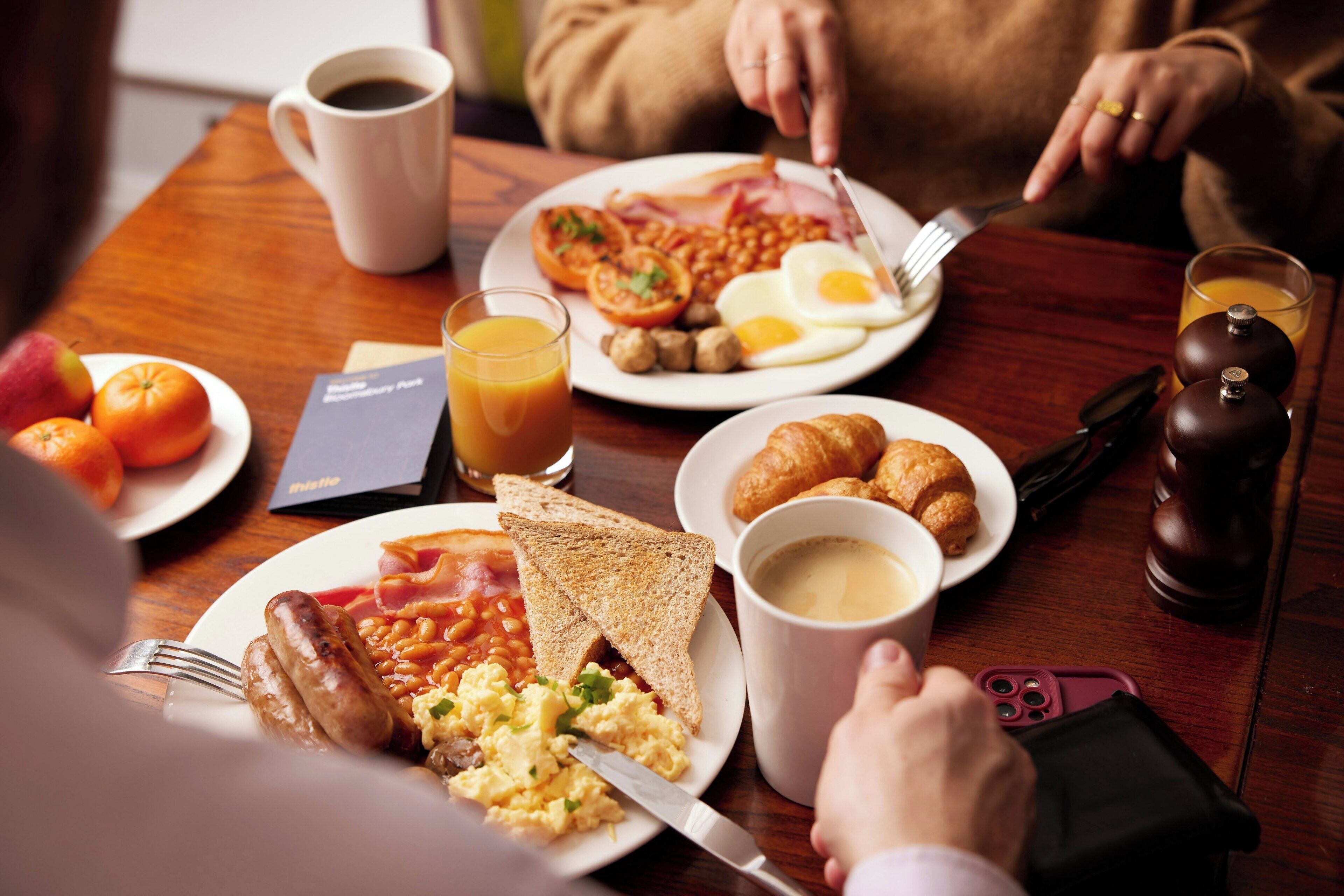 Une table mise pour le petit-déjeuner, avec des assiettes de nourriture, une tasse de café et un verre de jus.