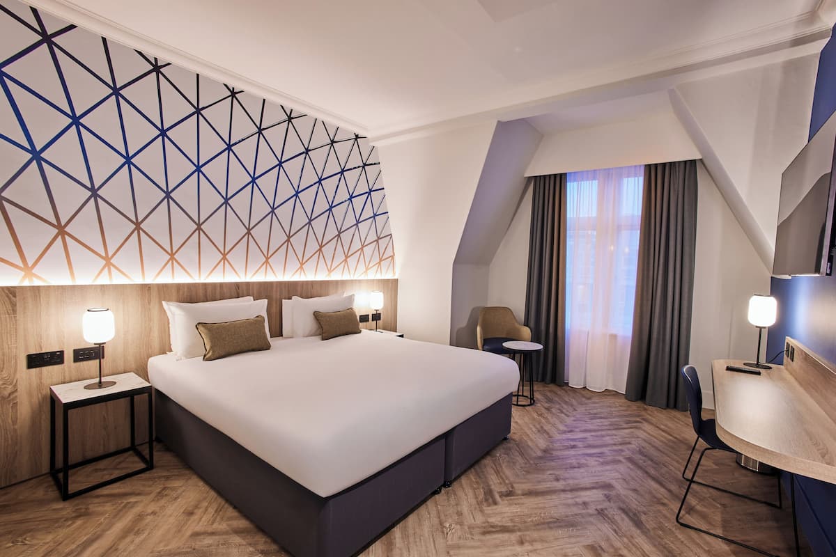 Una habitación de hotel moderna con una cama grande, un escritorio y una silla.