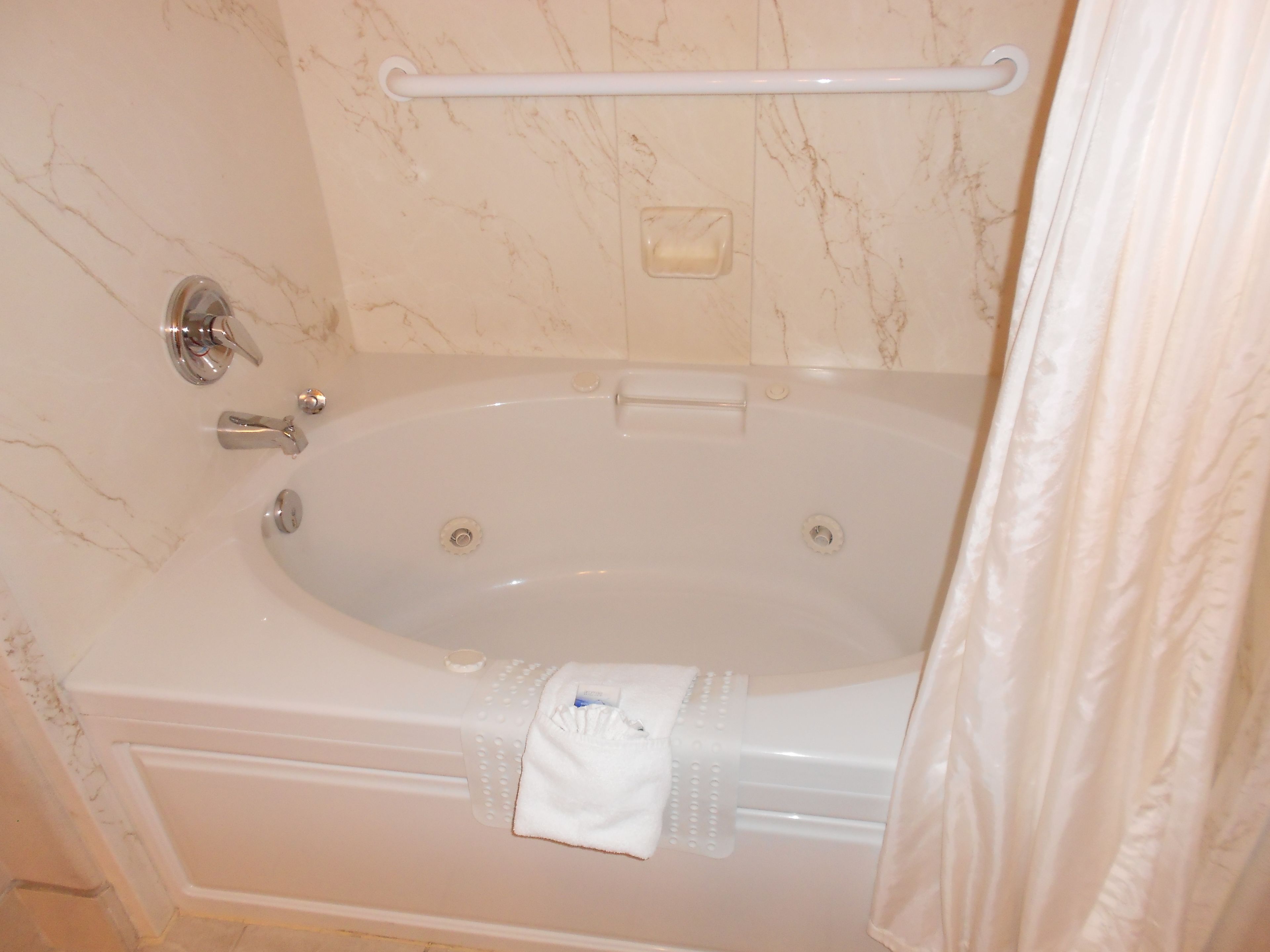Un baño con bañera, barandilla y toallero.
