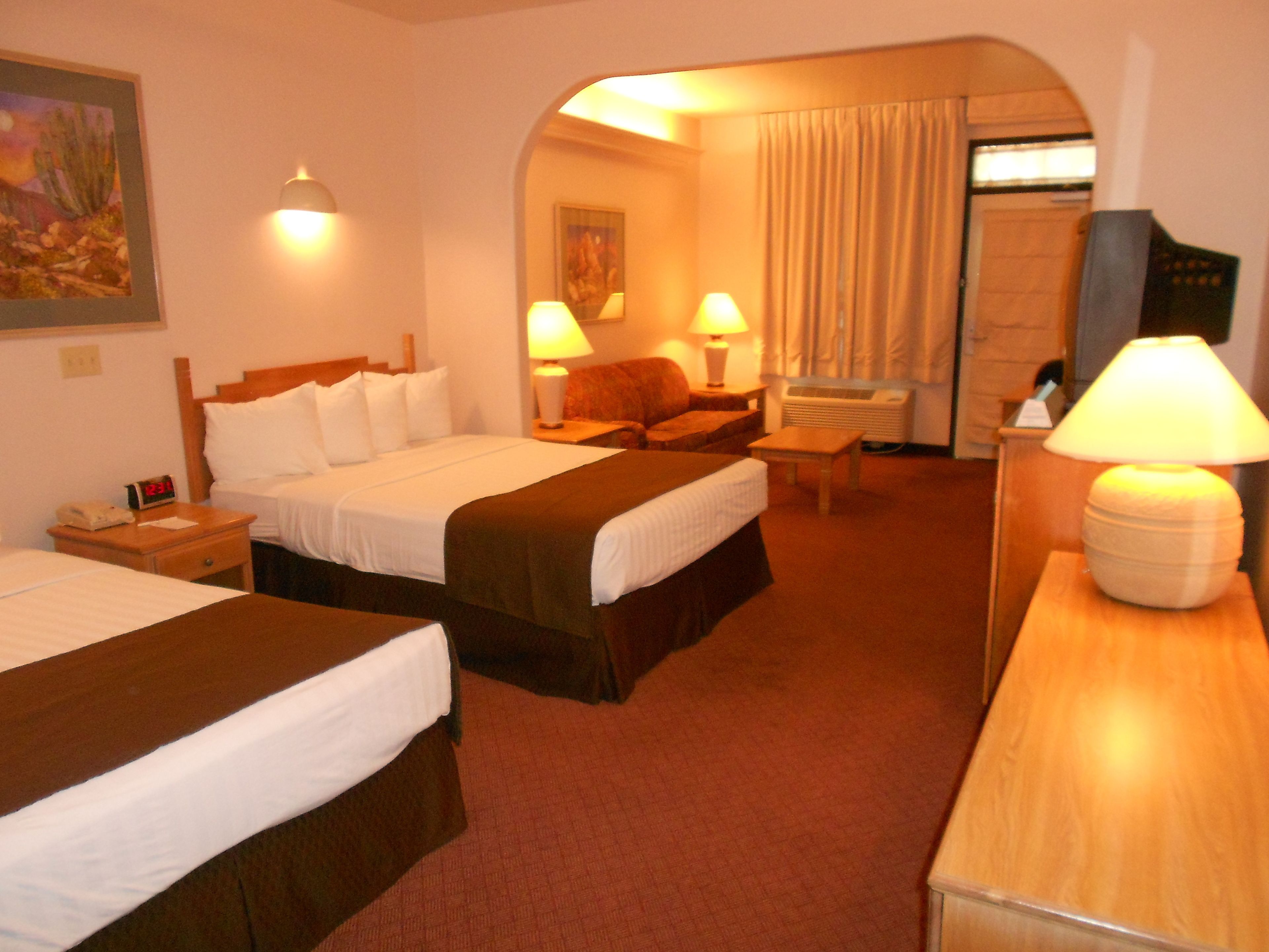 Une chambre d’hôtel avec deux lits, un bureau, une chaise et une lampe.