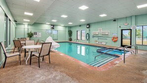 A pool area with a tiled floor, a pool, and a table with chairs.