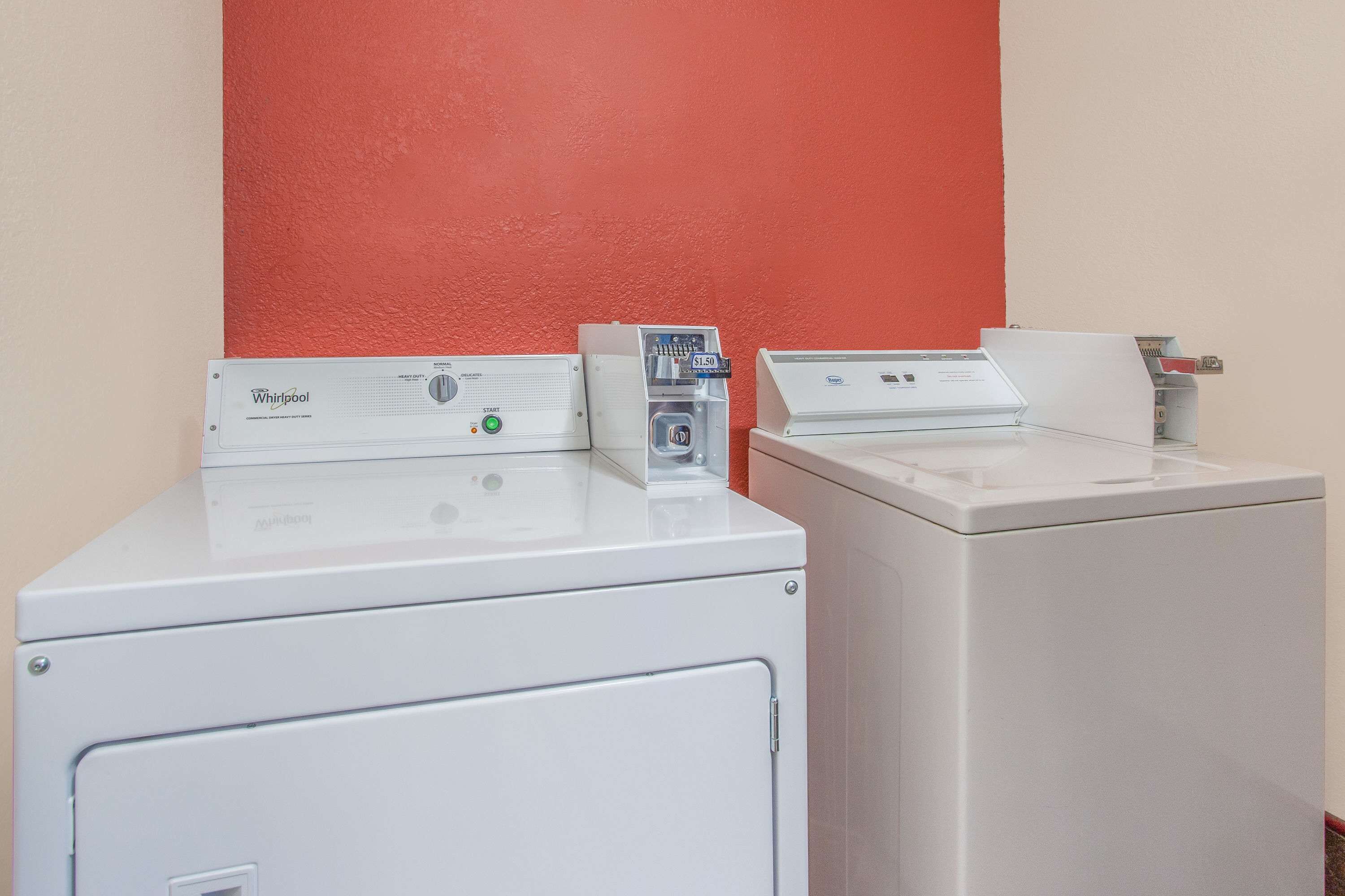 A laundry area with two washers and a dryer, a control panel, and a price tag.