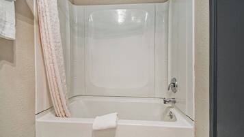 A white bathtub with a shower curtain, a towel, and a faucet.