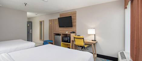 Een hotelkamer met twee bedden, een bureau met stoel, een aan de muur bevestigde televisie, een bureaulamp en een verwarming.