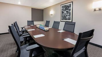 A conference room with a long table, black chairs, and a framed picture on the wall.