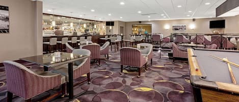 Una hall d'albergo con tavolo da biliardo, zona bar e diverse aree relax.