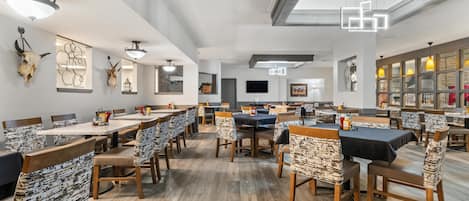 A spacious dining area with multiple tables and chairs, a ceiling fan, and wall-mounted artwork.
