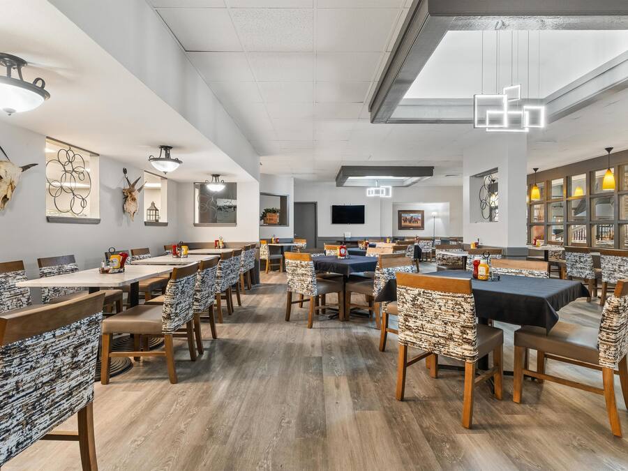 A spacious dining area with multiple tables and chairs, a ceiling fan, and wall-mounted artwork.