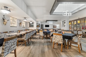 A spacious dining area with multiple tables and chairs, a ceiling fan, and wall-mounted artwork. - Red Lion Hotel & Conference Center Cheyenne (Cheyenne)