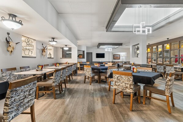 A spacious dining area with multiple tables and chairs, a ceiling fan, and wall-mounted artwork. - Red Lion Hotel & Conference Center Cheyenne (Cheyenne)