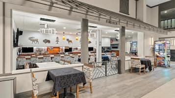 A restaurant with a modern interior, including a bar area and a seating section with tables and chairs.