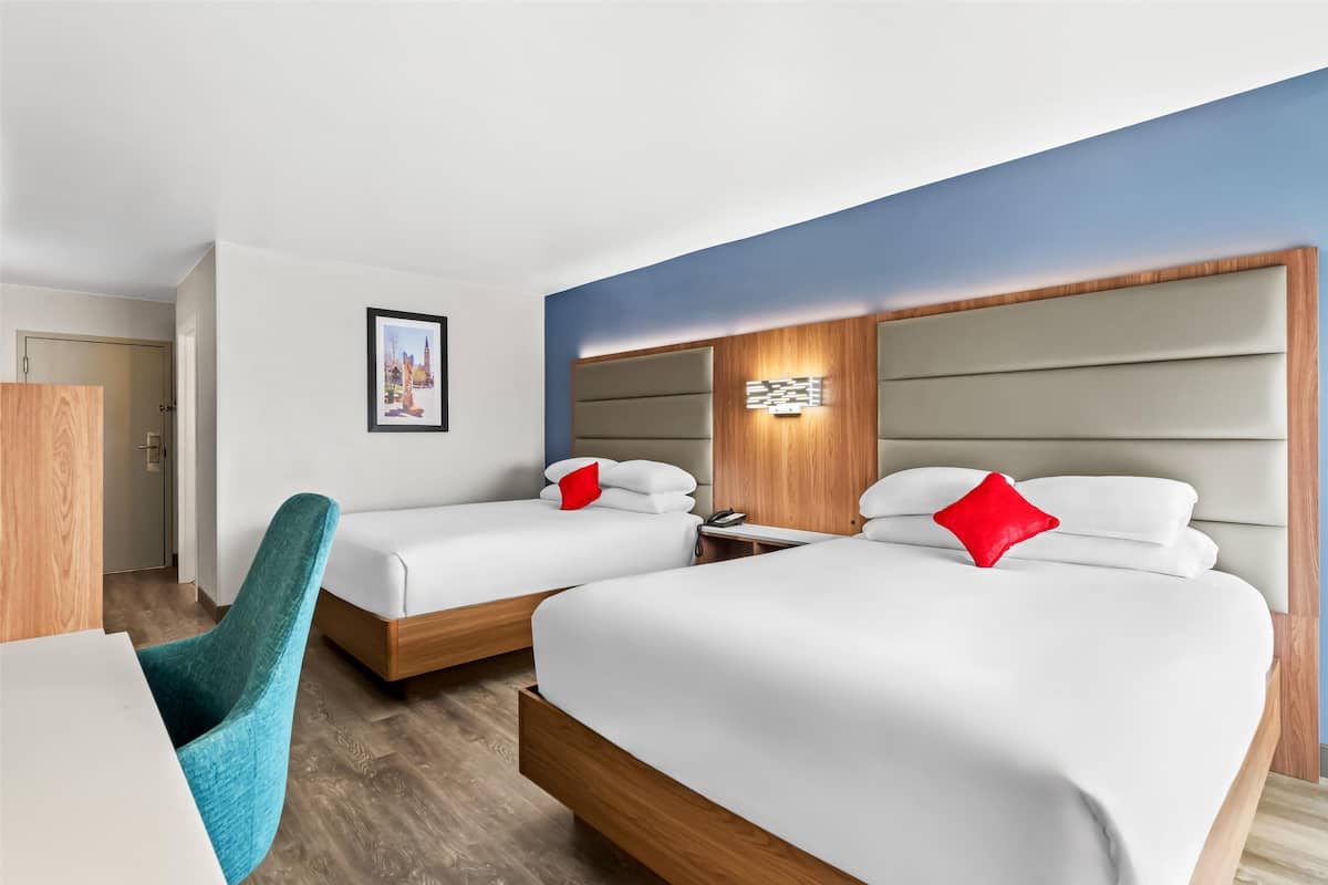 A hotel room with two beds, a desk, and a chair.