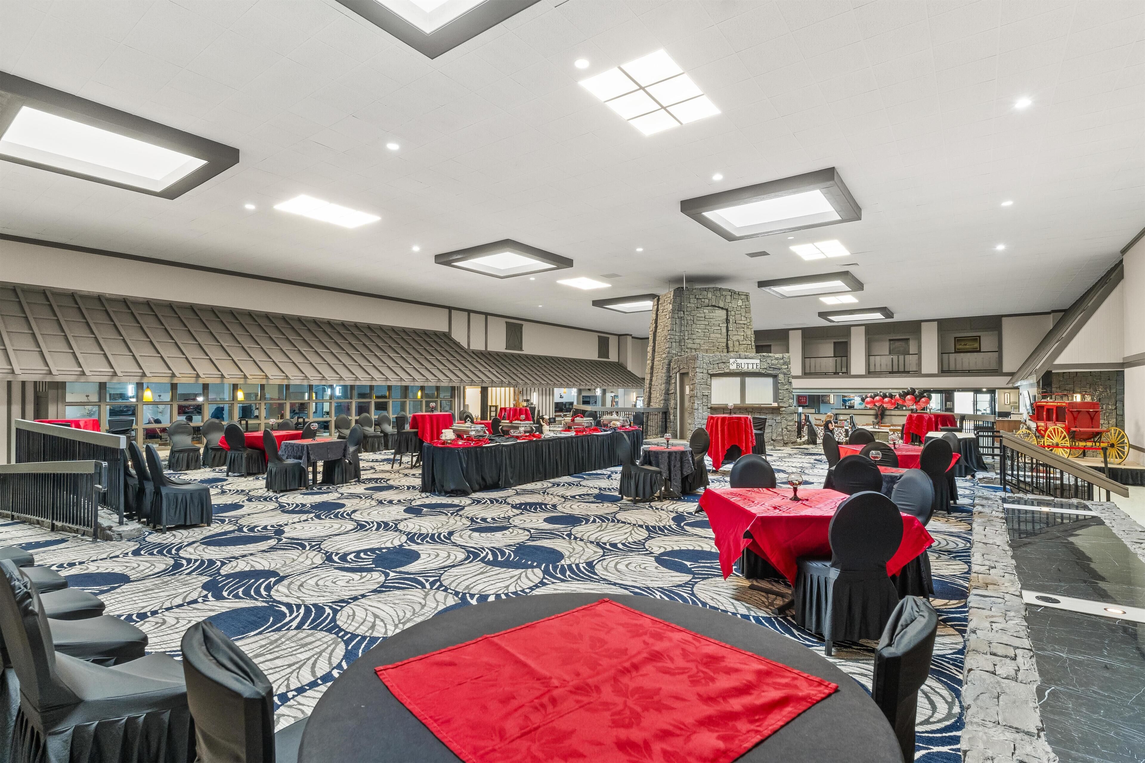 A spacious banquet hall with high ceilings, multiple tables set for dining, and a decorative stone feature.