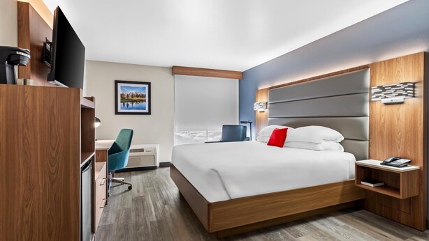Une chambre d’hôtel moderne équipée d’un grand lit, d’un bureau, d’une chaise et d’un téléviseur.