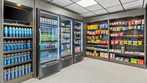 Un magasin bien éclairé, doté de distributeurs de boissons réfrigérés, d’étagères remplies d’en-cas et d’une variété de produits emballés.