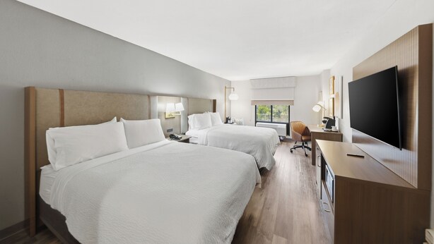 A hotel room with two beds, a desk, a TV, and a window with a view. - Holiday Inn Atlanta-Northlake by IHG (Atlanta)