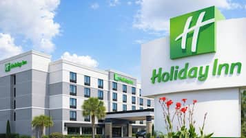 Un hotel Holiday Inn con una fachada moderna, varios pisos y un cielo despejado.