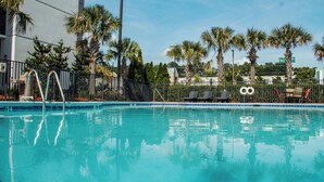 A swimming pool with clear water, surrounded by palm trees and a fence. - Holiday Inn Atlanta-Northlake by IHG (Atlanta)