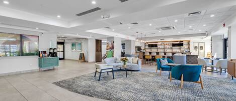 A spacious lobby with a seating area, a kitchenette, and a bakery.