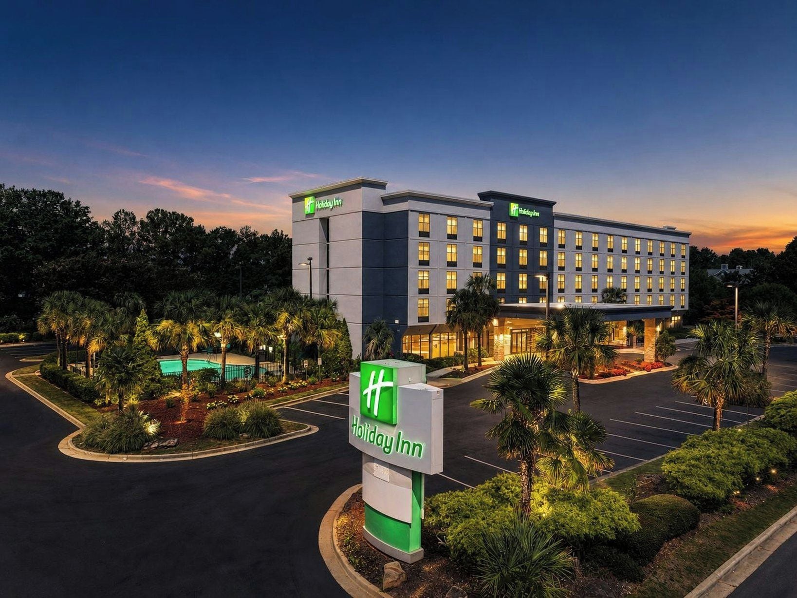 A Holiday Inn hotel with a modern design, featuring a large parking lot and well-maintained landscaping.