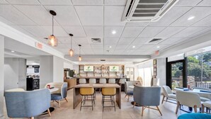A modern hotel lobby with a central bar area, seating arrangements, and exit signs. - Holiday Inn Atlanta-Northlake by IHG (Atlanta)