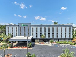 A Holiday Inn hotel with a flat roof, multiple floors, and a parking lot with marked spaces.