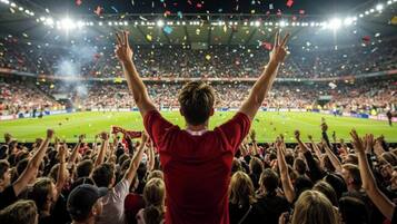 A stadium filled with spectators, some raising their hands in celebration.