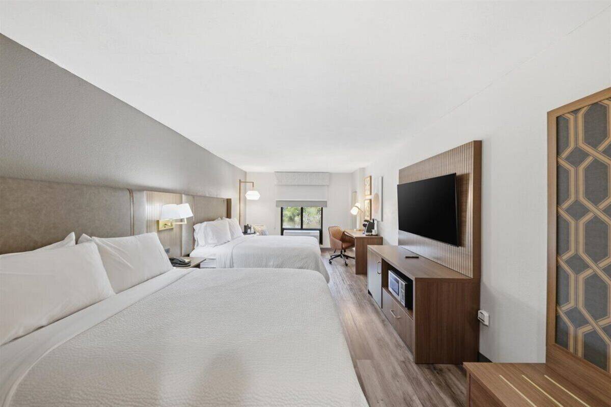 Une chambre d’hôtel avec deux lits, un bureau, une télévision et une fenêtre.