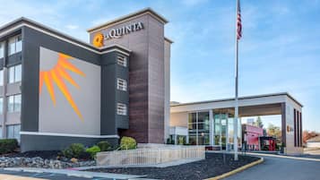 A hotel with a modern design, featuring a prominent sun logo on the facade and a flagpole with an American flag.