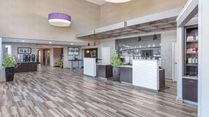 Un hall d’entrée spacieux au design moderne, comprenant un comptoir d’accueil, un espace salon et un grand espace ouvert doté d’un sol à motifs.