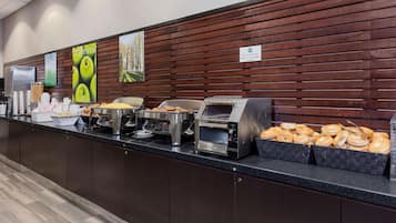 A buffet counter with various food items and a coffee station.