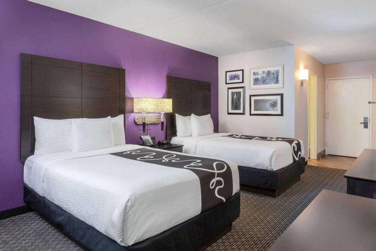 Una habitación de hotel con dos camas, un escritorio y una puerta.