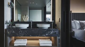 Un baño moderno con dos lavamanos, un espejo grande y un banco de madera con toallas.