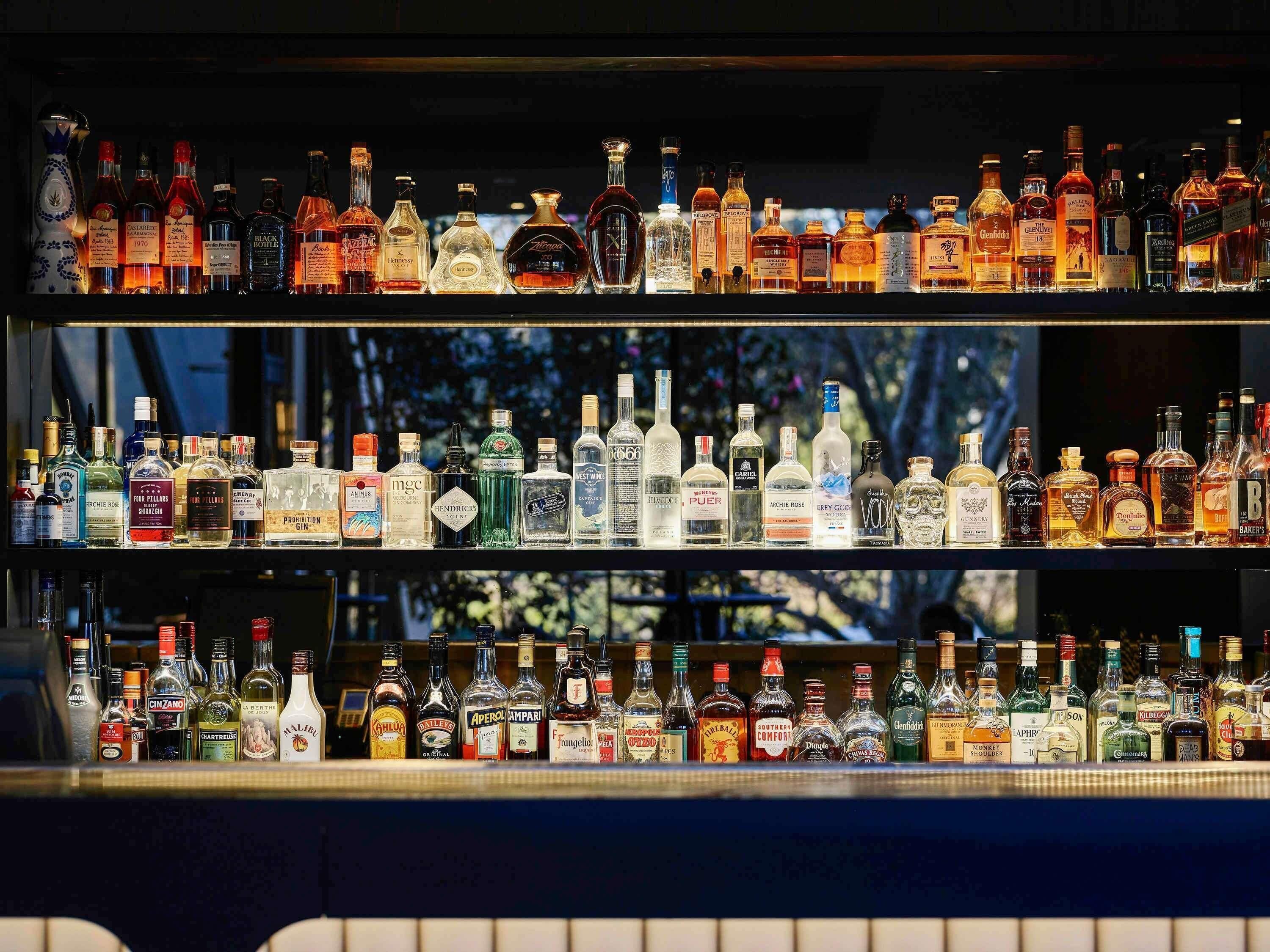 Un bar con varias estanterías llenas de diferentes botellas de licores.