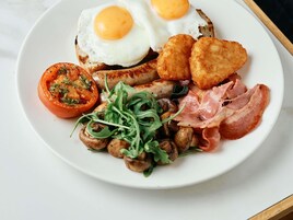 Prato com ovos, salsichas, cogumelos, bacon e tomate.