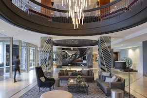 A spacious lobby with a central seating area, a spiral staircase, and a modern chandelier.