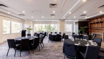 A conference room with round tables, black chairs, and a podium.