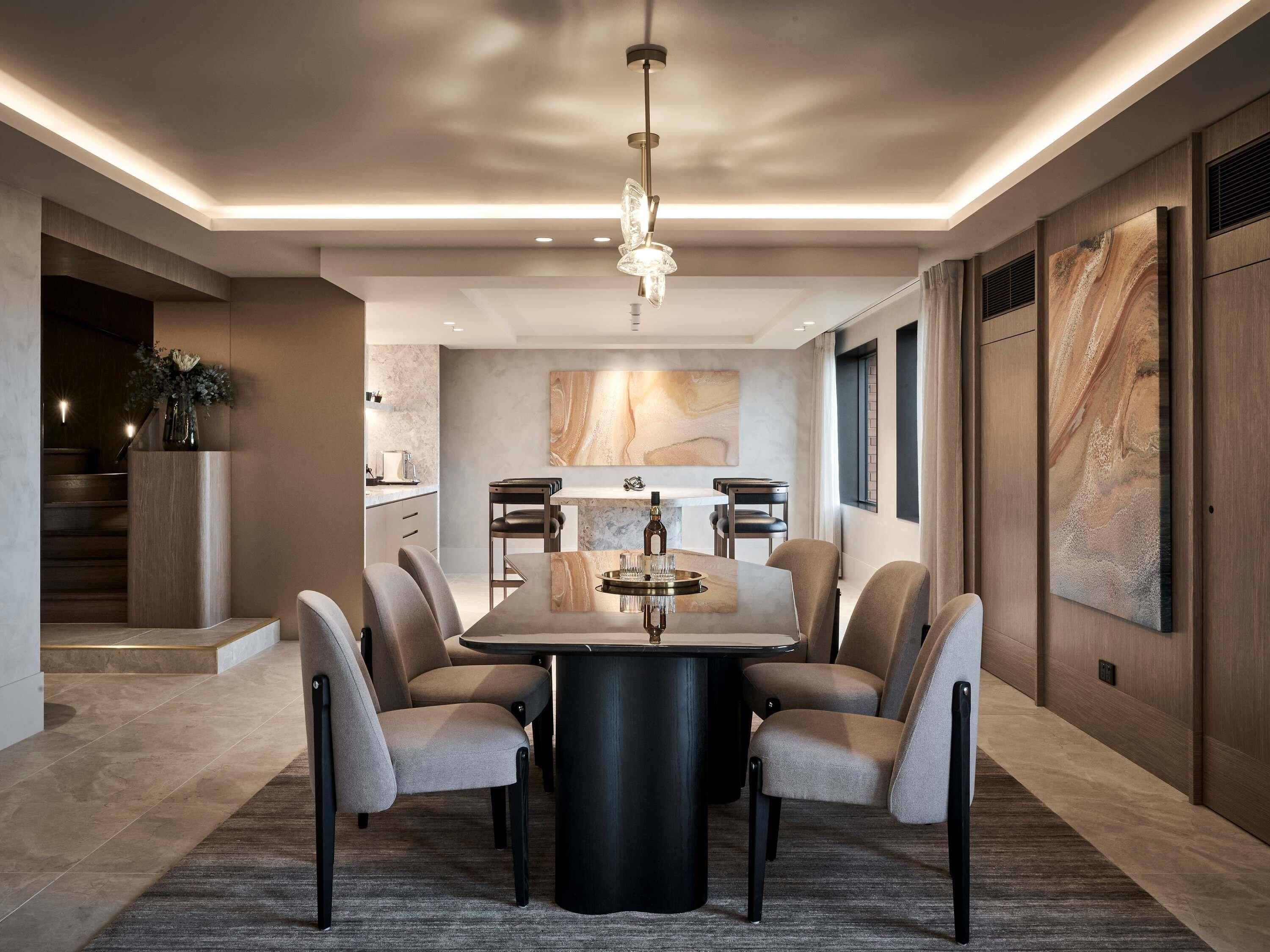 A modern dining area with a central table, chairs, and a chandelier.