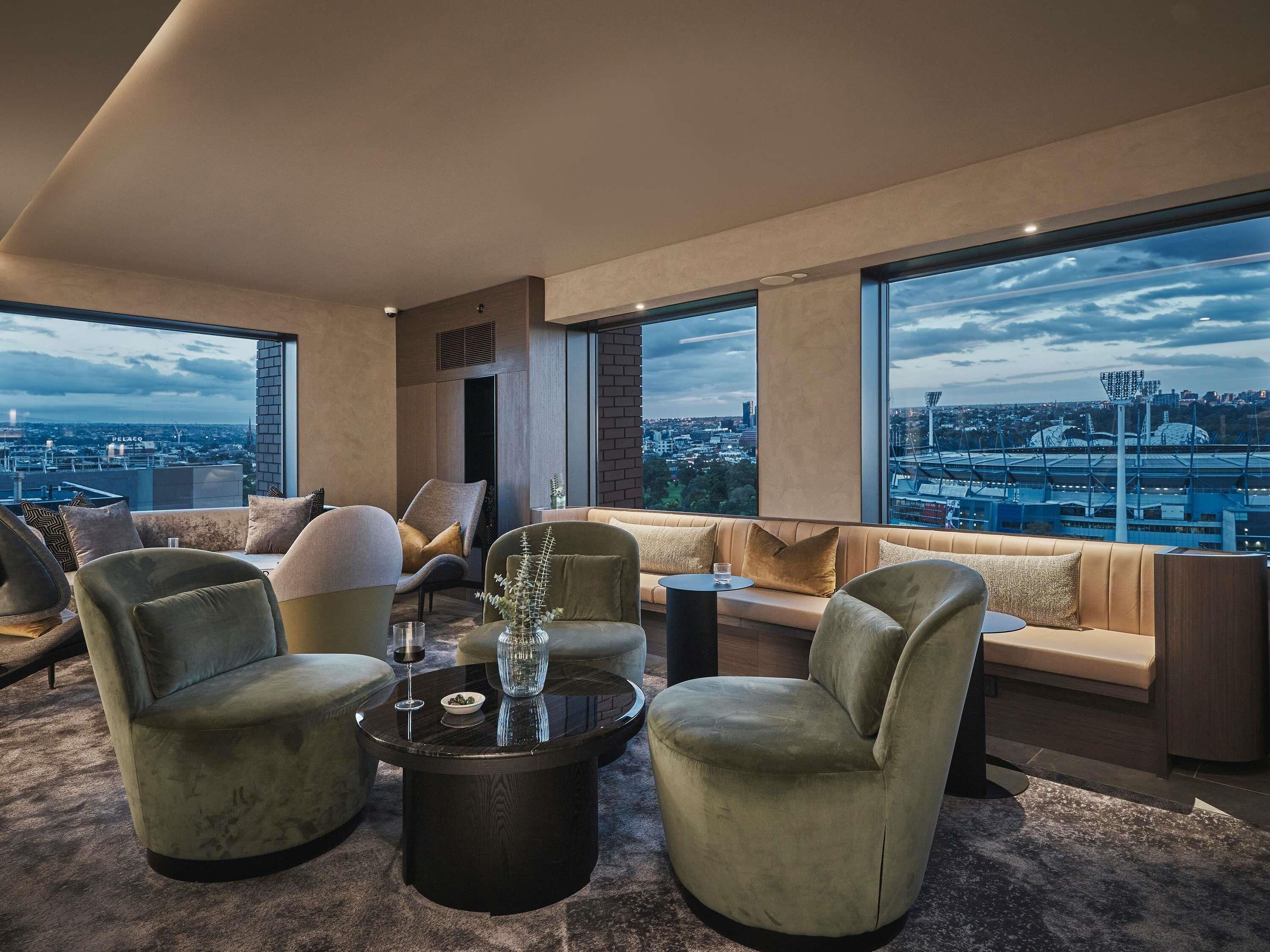 A modern living room with a city view, large windows, and a mix of seating options.