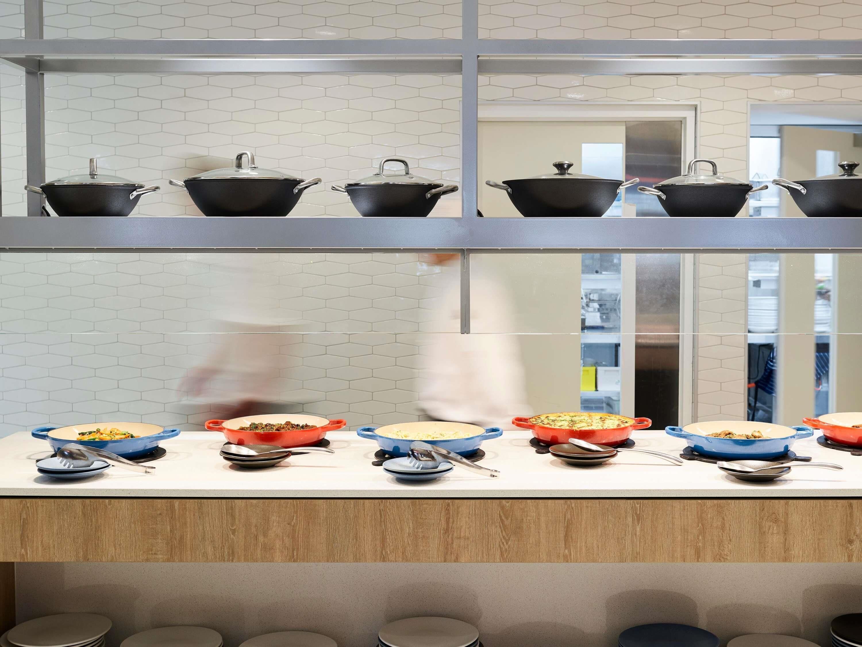 Cozinha com várias estações de preparo, cada uma com um wok e uma variedade de pratos.