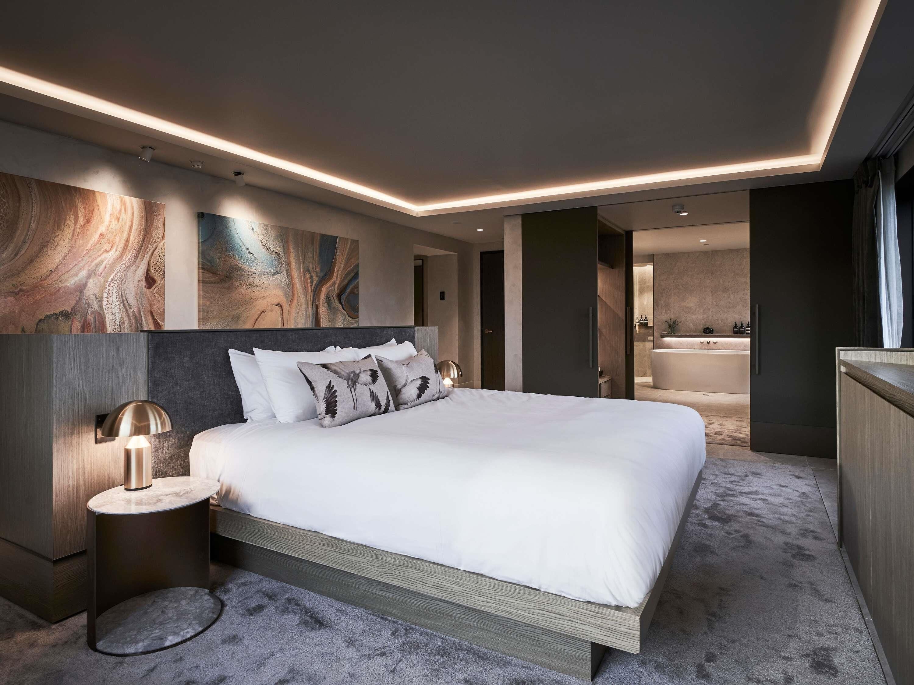 Un dormitorio moderno con una cama grande, lámparas de noche y vistas al baño.