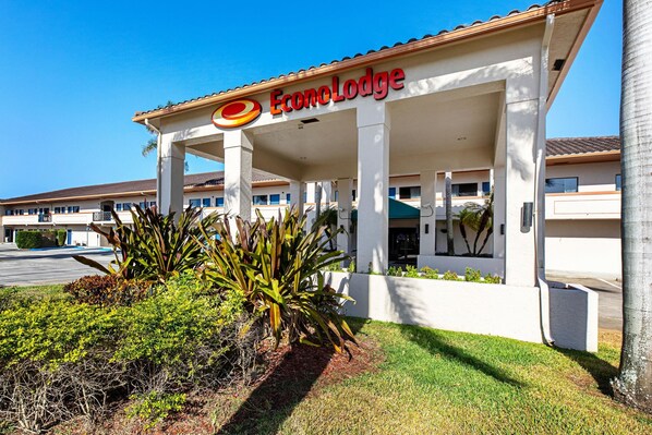A hotel named EconoLodge with a covered entrance, palm trees, and a clear blue sky.
