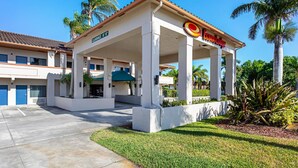 A gas station with a canopy, palm trees, and a clear blue sky.