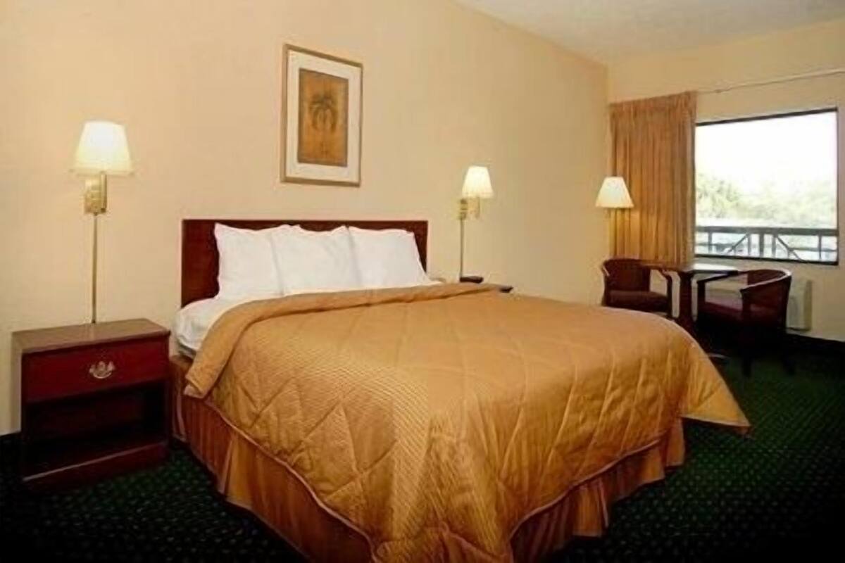 A hotel room with a large bed, two bedside tables, a desk, and a chair.