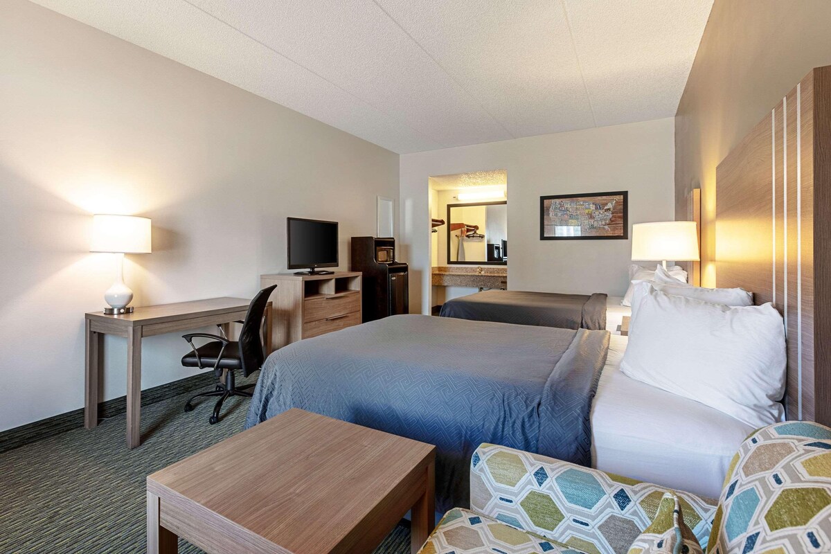 Une chambre d’hôtel comprenant un lit, un bureau avec une chaise, une télévision et un miroir dans la salle de bain.