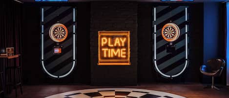 A dartboard with a neon sign that reads "PLAY TIME" in the center of a room with a checkered floor pattern.