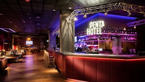 A bar area with a 'PENTA HOTEL' sign, wooden flooring, and bar stools. - pentahotel Reading (Reading)